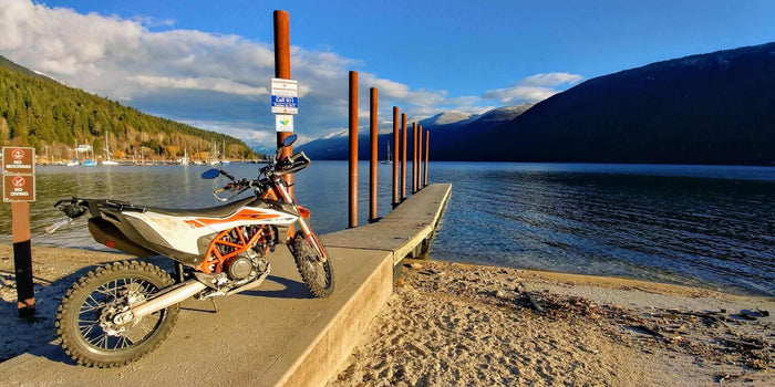 KTM dual sport bike parked on a lakeside breakwater at sunset near Kokanee Glacier Provincial Park