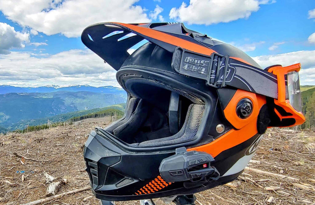 Dual sport helmet fitted with a UClear Motion 6 intercom and goggles on a clearcut mountain ridge