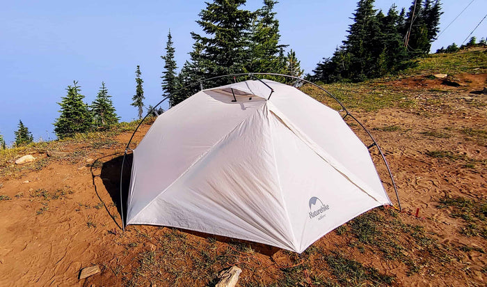 Naturehike Vik tent pitched on a dirt ridge among subalpine trees at dusk