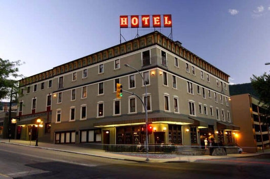 The historic four-storey Hume Hotel in Nelson BC with its red rooftop HOTEL sign at dusk