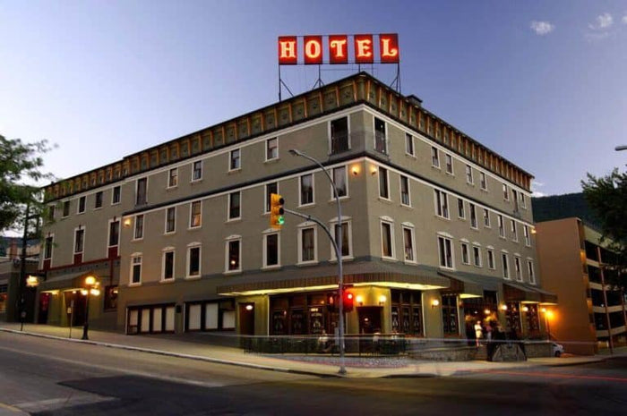 The historic four-storey Hume Hotel in Nelson BC with its red rooftop HOTEL sign at dusk