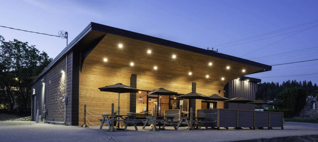 Wild North Brewing taproom at dusk, timber building with patio umbrellas and picnic tables under string lights
