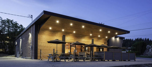 Wild North Brewing taproom at dusk, timber building with patio umbrellas and picnic tables under string lights