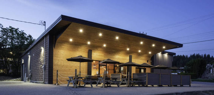 Wild North Brewing taproom at dusk, timber building with patio umbrellas and picnic tables under string lights