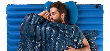 Naturehike down sleeping bag wrapped around a man resting on an inflatable pad with a camp pillow