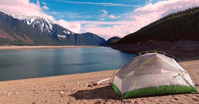 Naturehike Star River tent pitched on a sandy reservoir shore below snow capped mountains