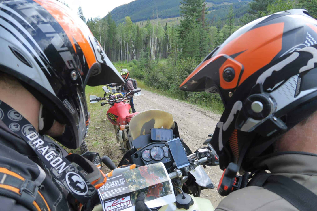 POV selfie of two riders in adventure helmets stopped on a gravel forest road during Wanduro