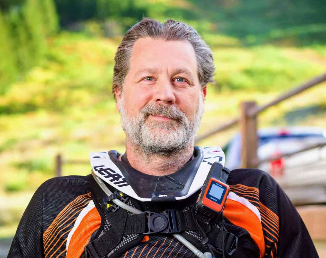Adventure rider in Leatt neck brace and chest armor with a satellite messenger, mountains behind