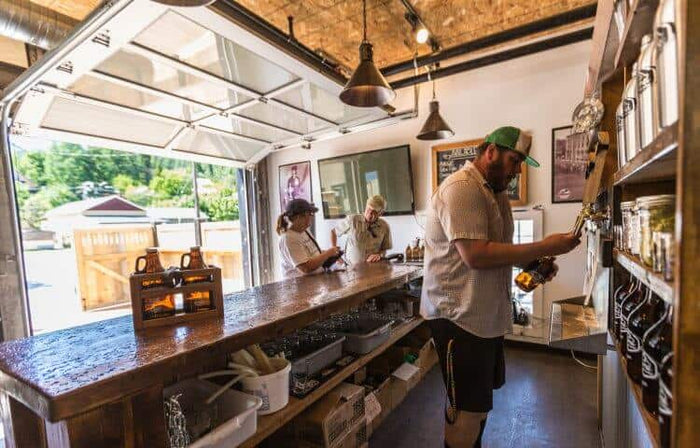 Bartender pouring a growler behind the bar at Erie Creek Brewing taproom