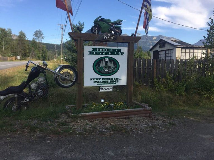 Riders Retreat roadside sign with a green sportbike mounted on top and a chopper parked beside it