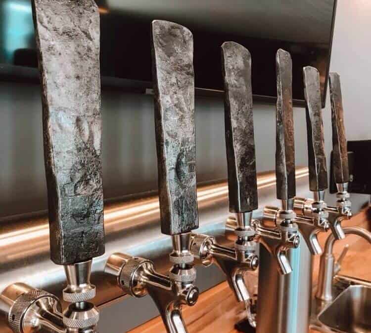 Row of forged metal tap handles on the taps at Fisher Peak Brewing