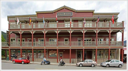 The historic red and cream Kaslo Hotel with flag-lined balcony and motorcycles parked out front