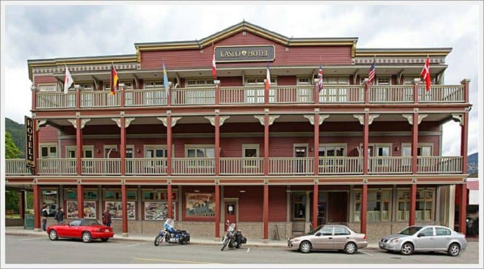 The historic red and cream Kaslo Hotel with flag-lined balcony and motorcycles parked out front