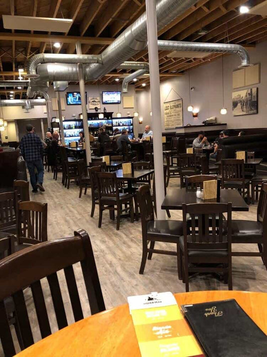 Open dining room with timber ceilings and dark wood tables at Fisher Peak Brewing