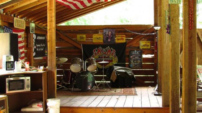 Covered timber stage with a drum kit, US flag and moto license plates at Riders Ranch