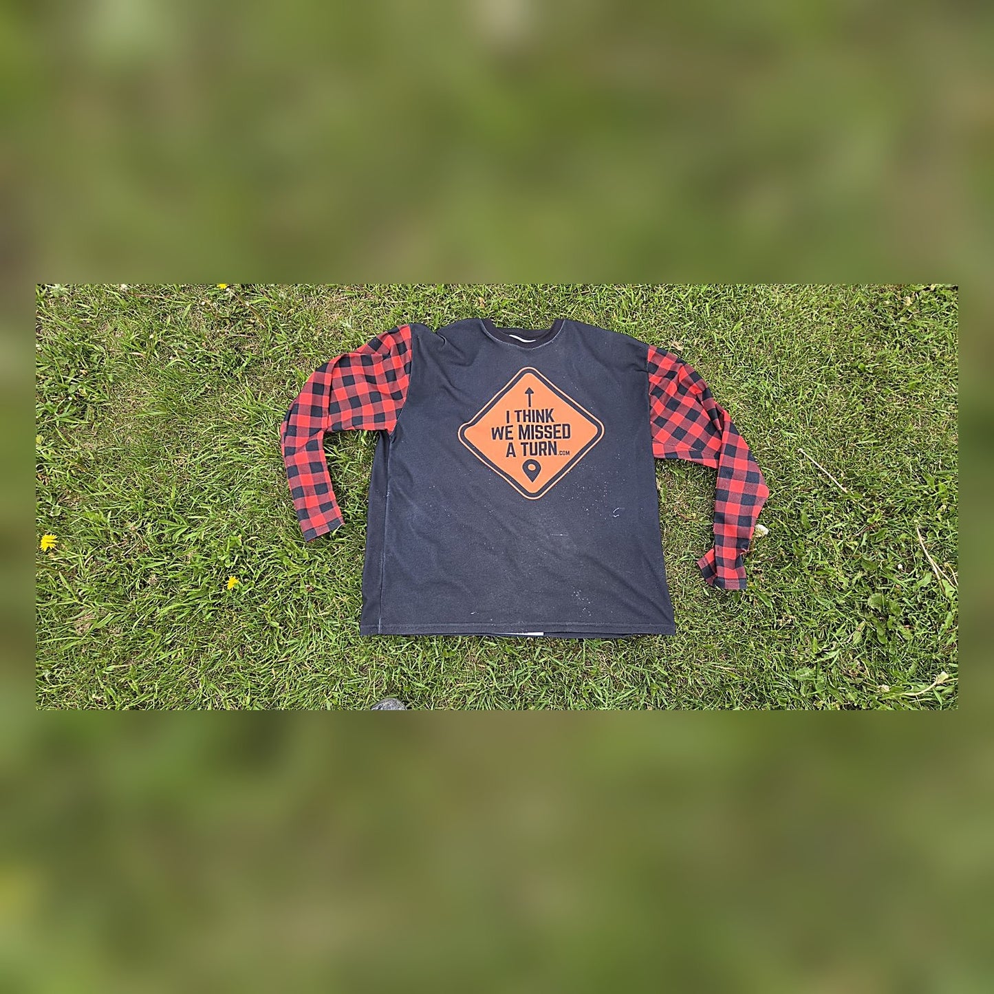 Front of the ITWMAT Lumbersquatch ADV jersey, black body with orange diamond logo and red plaid sleeves on grass
